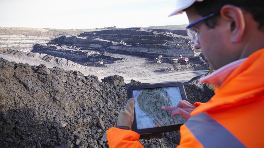 Worker sing digital tablet at the coal mine site, elevated view
