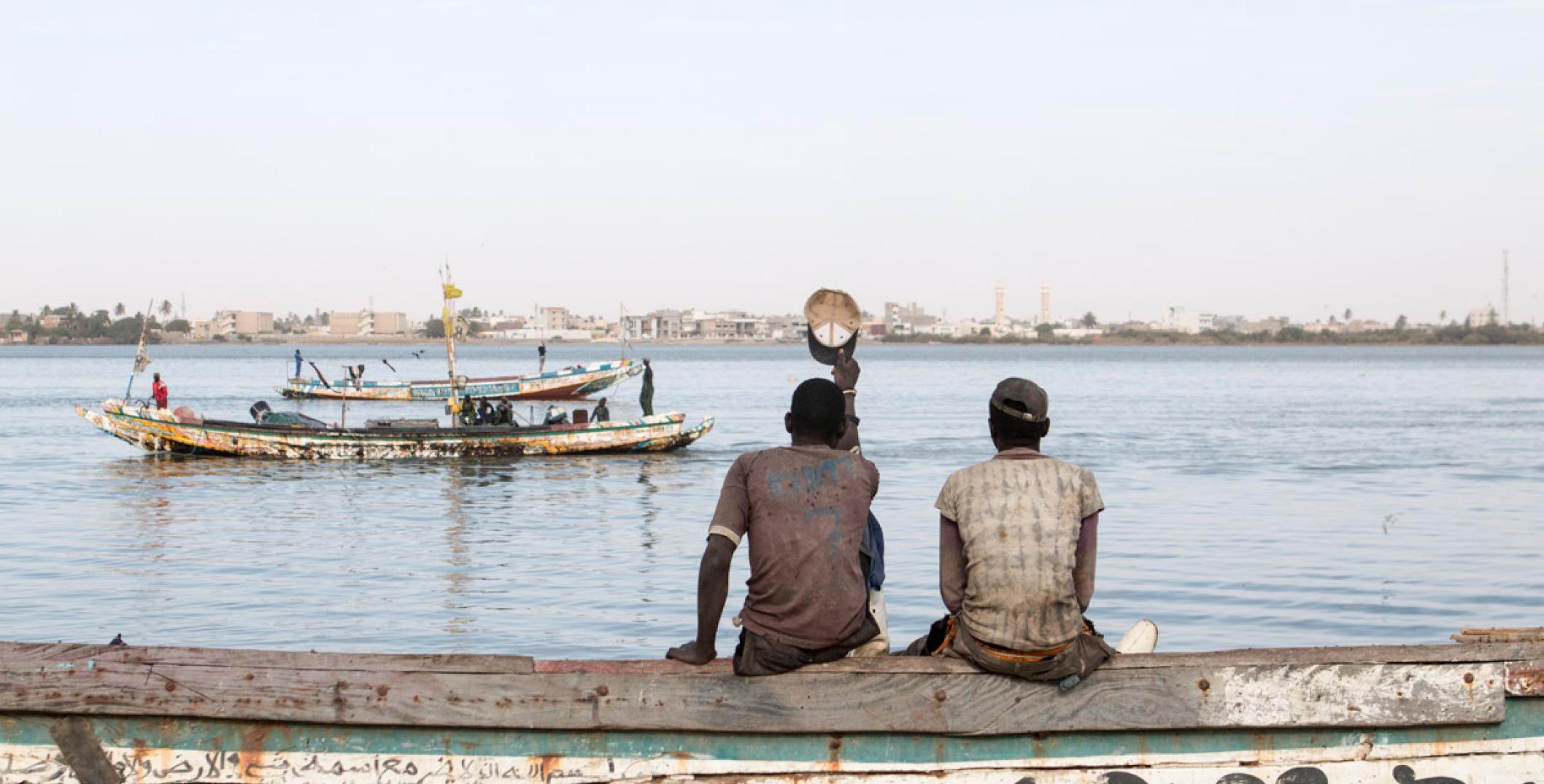 Two men sitting on the riverside in Saint Louis, Senegal