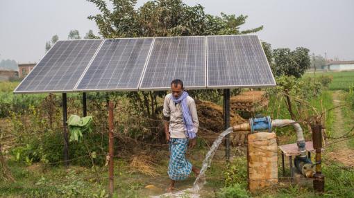 Farmer next to solar panel powering the irrigation pump, Nepal
