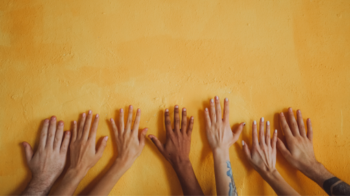 Diverse hands on top against the yellow wall 