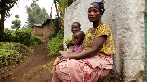 Single mother with two children sitting in a village in North Kivu, DRC